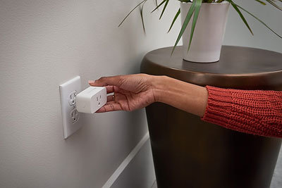  A smart plug being plugged into a wall outlet  